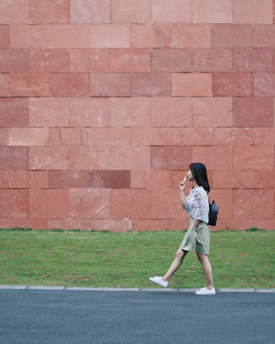 Woman speaking into her phone while walking past a red stone wall